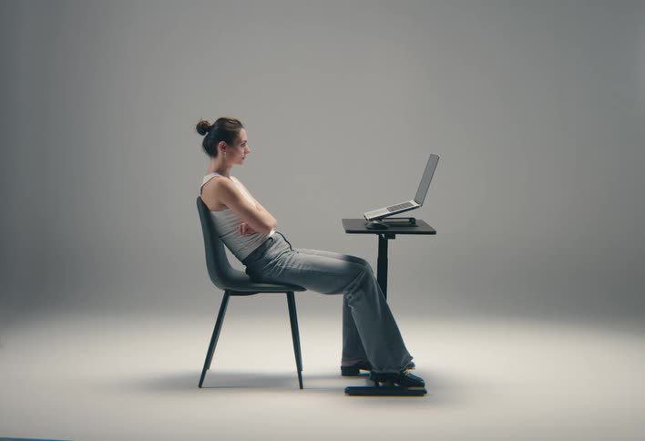 Woman sitting on a chair in front of a laptop on an adjustable desk