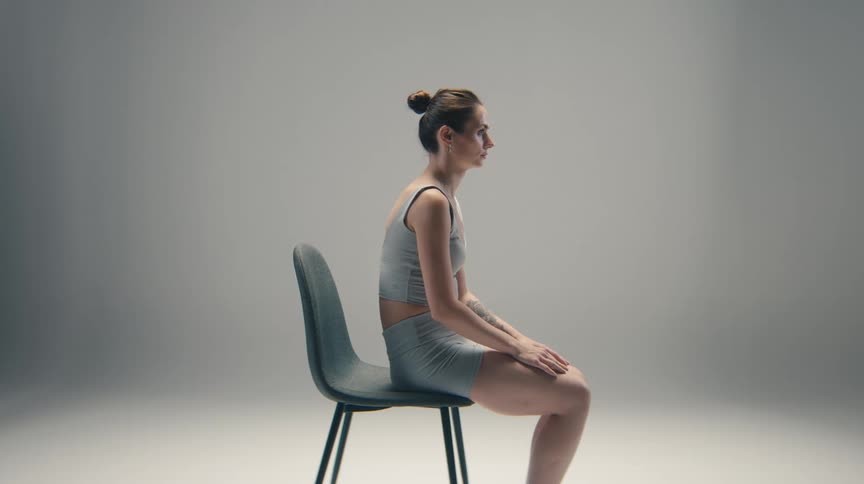A woman wearing athletic apparel sits motionless on a chair
