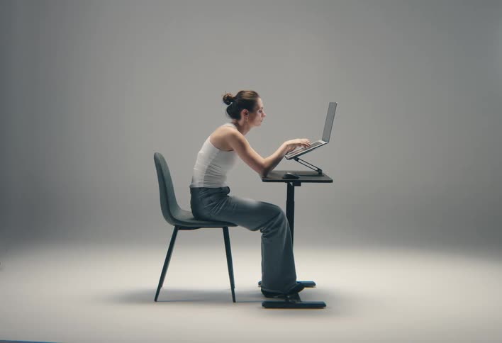 Woman typing on a laptop positioned on an adjustable desk