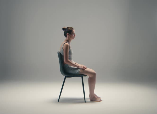 Woman seated in profile on a chair with feet resting on the floor