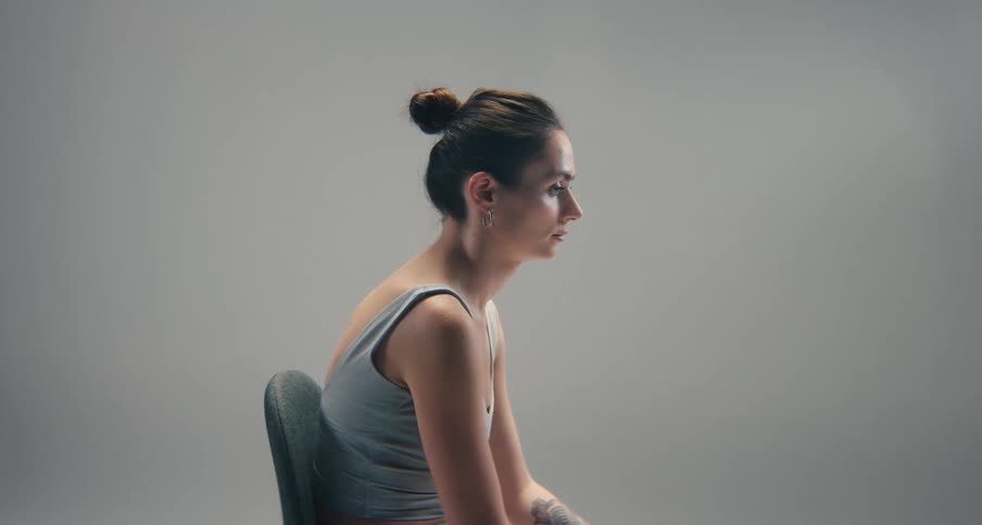 Woman sits motionless in a chair in a pale room
