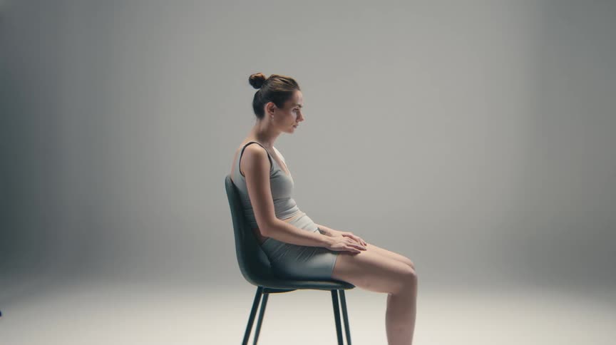 Woman seated in profile on a chair with hands resting on her legs