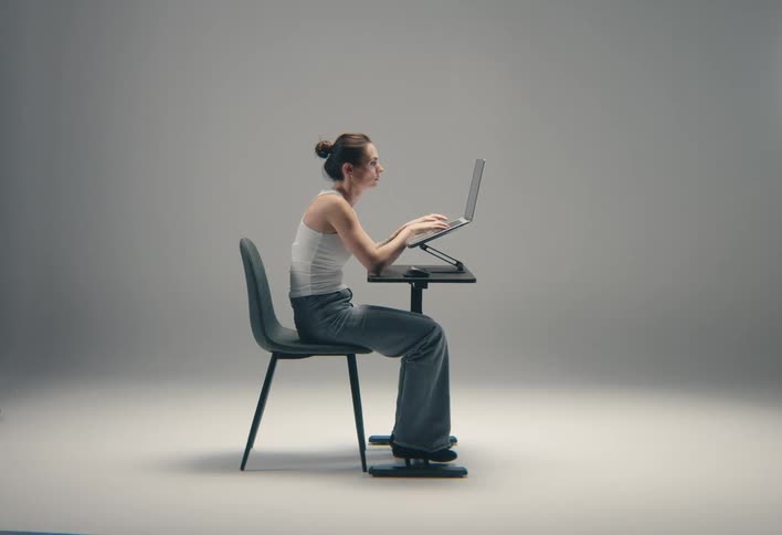 Woman uses a computer while sitting in a nearly empty room