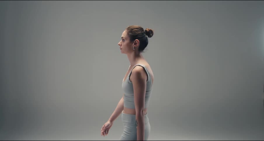 Woman walks in a studio with a plain gray background