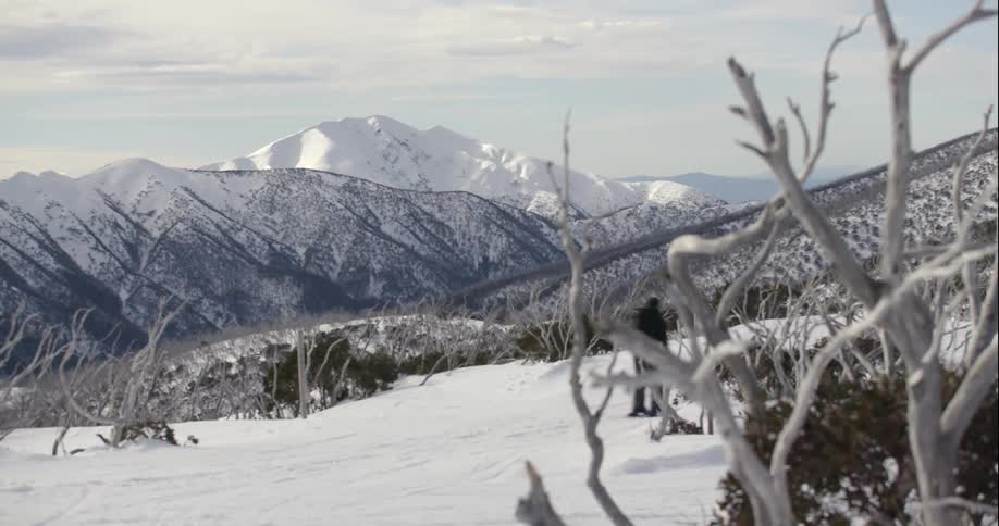 A man wearing a backpack skis across a mountain slope