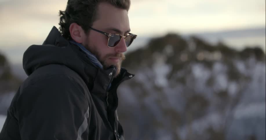 A man uses a smartphone while sitting on snow