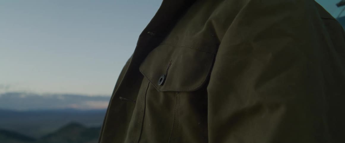 Closeup of a green jacket in a mountain landscape at dusk