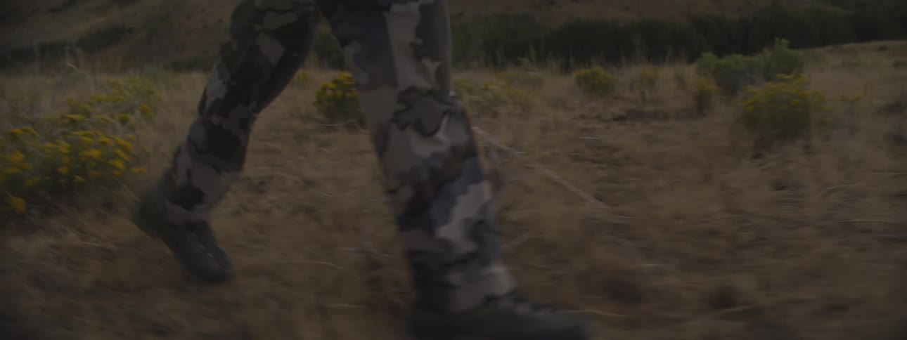 The man is hiking through the grass