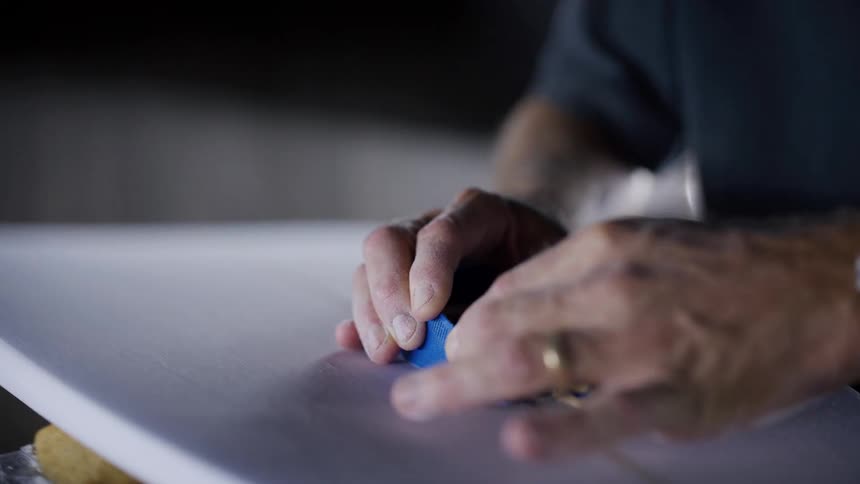 Man using a blue block to shape a white surface