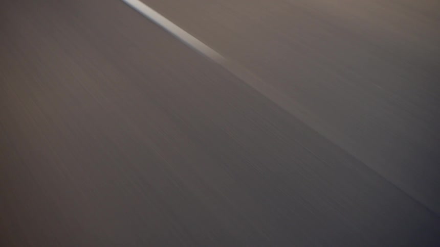 Solid white line on dark asphalt seen in motion