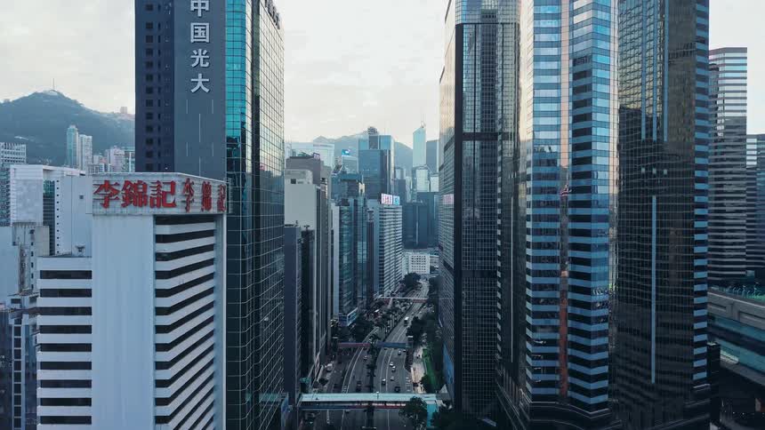 Modern towers and skyscrapers stand tall in the metropolitan sky as cars travel on the street