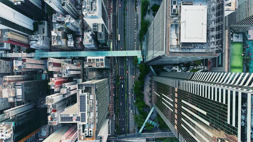 Traffic flows through the streets of a dense city lined with towering skyscrapers
