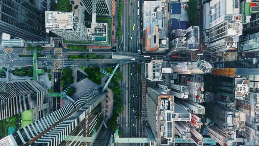 Aerial shot travels over busy city streets lined with towering dense skyscrapers and high rises