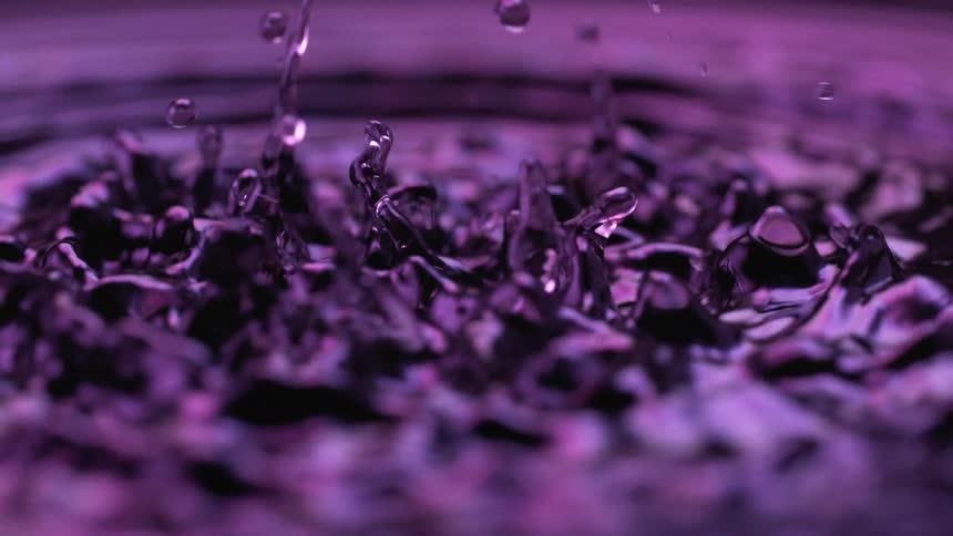 Purple liquid surface with raised splashes after impact