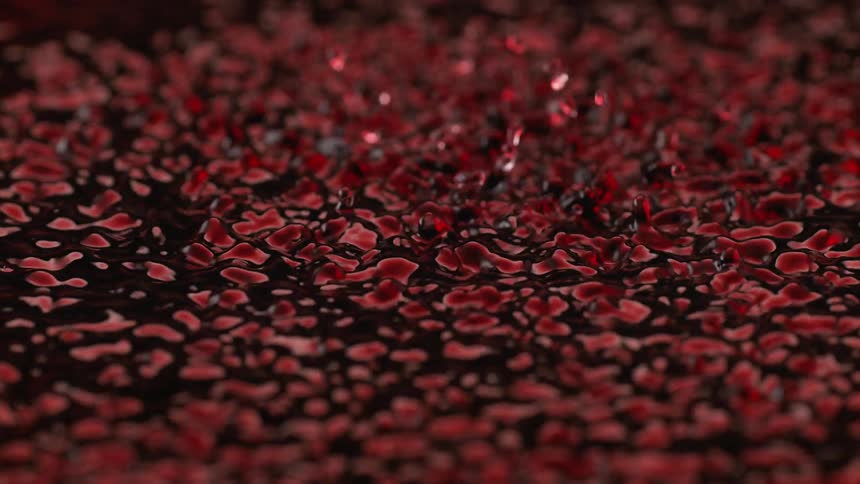 Red droplets scattered on a dark surface forming irregular patterns