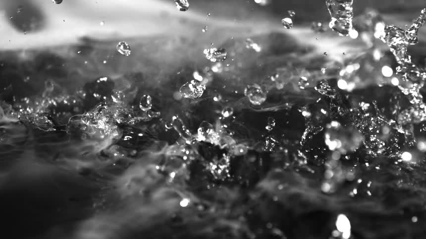 Water droplets splash chaotically into a dark misty pool
