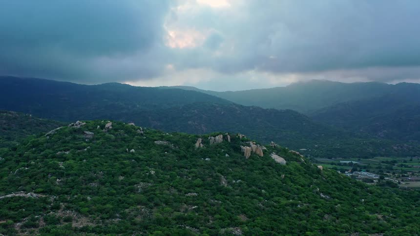 Green hills with rocky outcrops under a sky covered by dense clouds