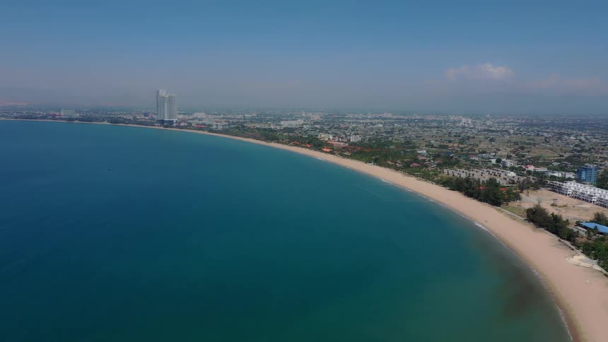 Aerial view of a curved beach beside an urban area