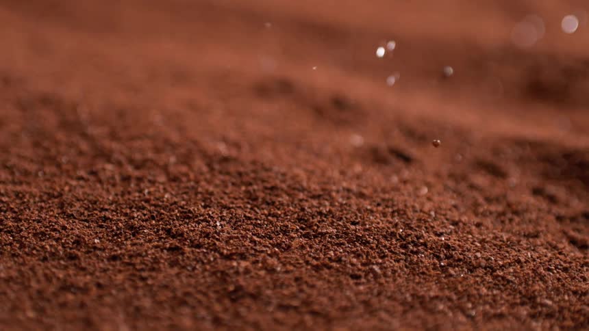 Fine brown powder with small droplets falling onto the surface