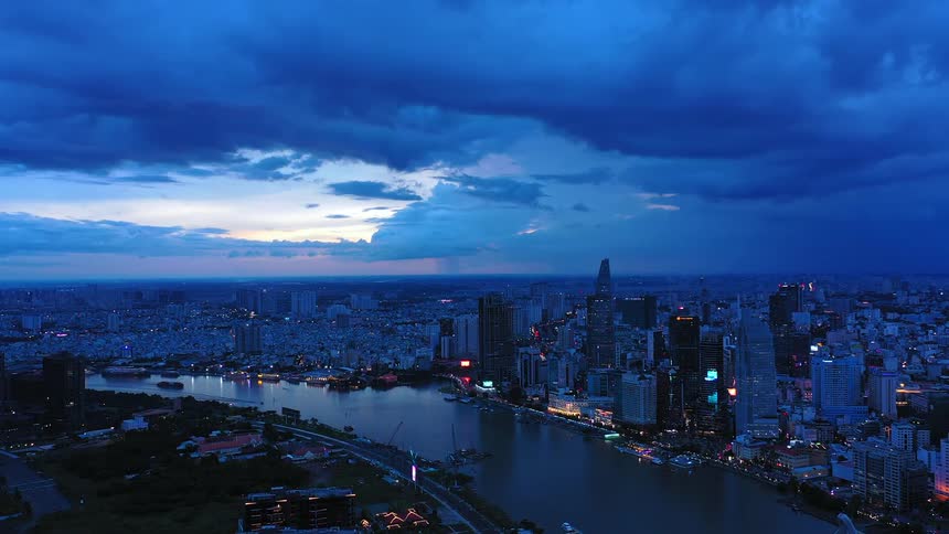 Aerial view of a metropolitan city on the coast of a river with boats on the water and traffic on the streets