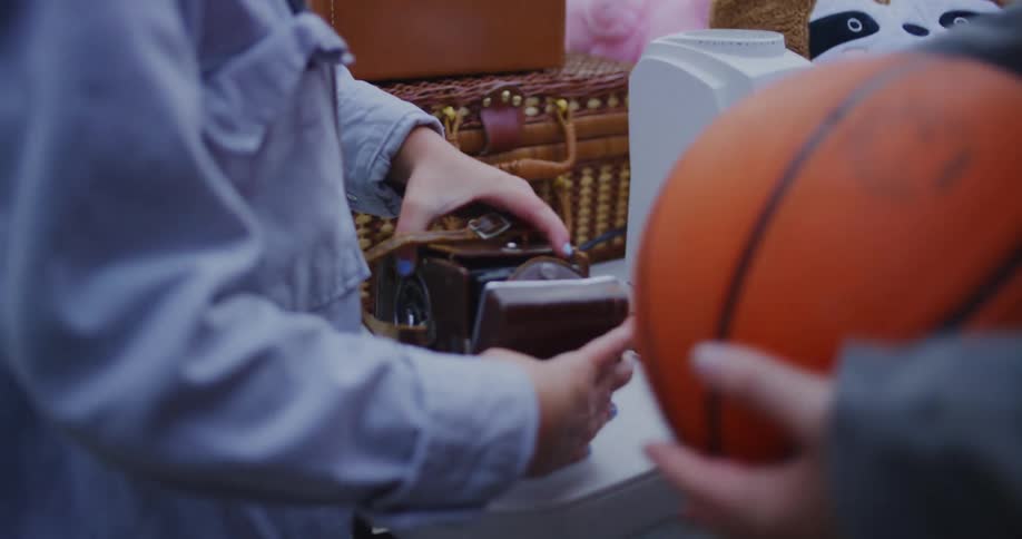 Hands hold and inspect a small electric device on a table with other items