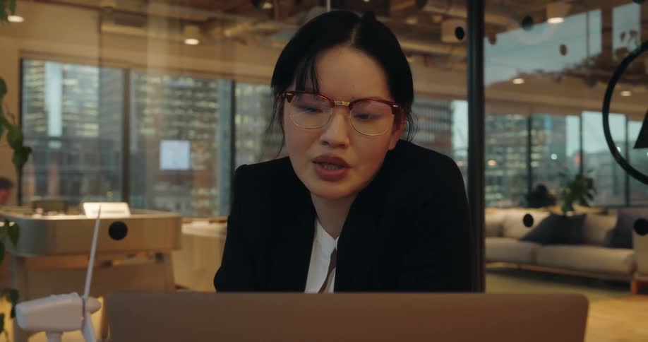 Woman adjusts her glasses while looking at the laptop