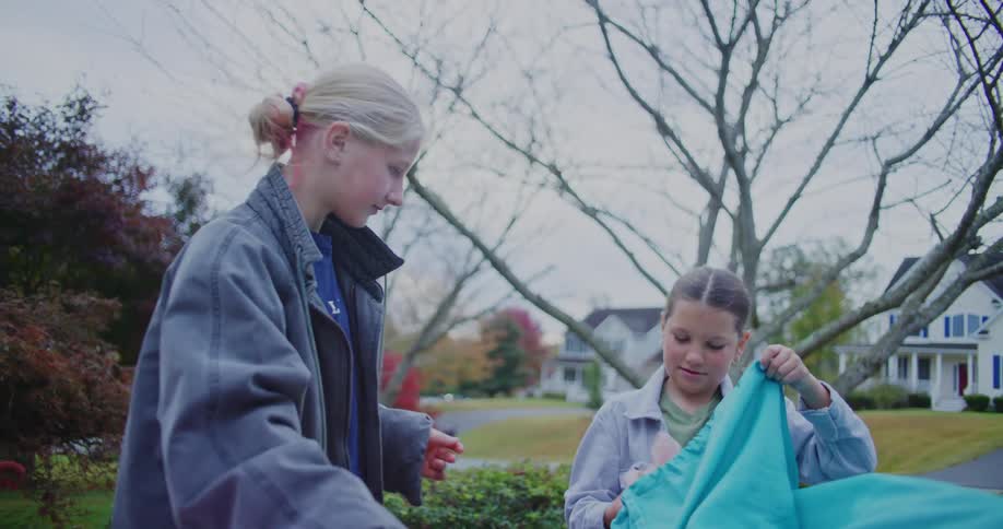 Children organize a toy and a blue bag on a table in a residential area