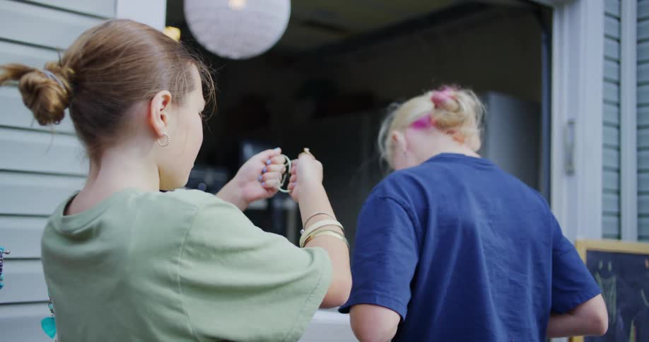One girl plays with some bracelets while showing her friend