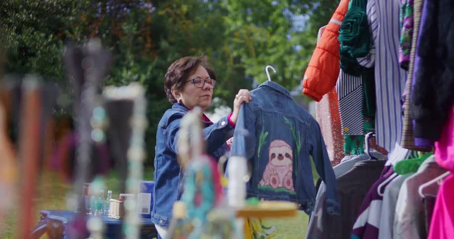A person shops through clothing on a rack at an outdoor suburban garage sale