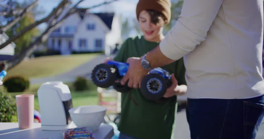 Adult sets up and hands a toy car to a boy