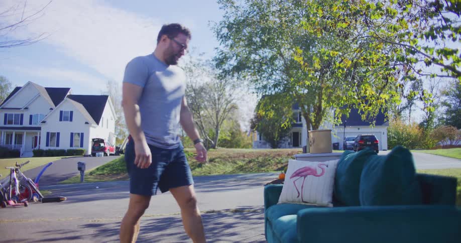 Man tests a couch displayed at an outdoor thrift sale