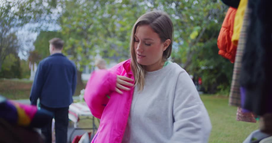 A woman tries on discounted clothes at an outdoor yard sale