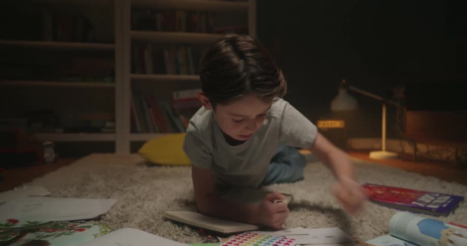 The boy is reading books and taking notes