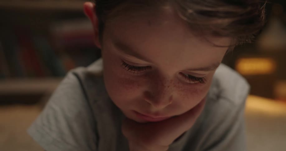 Young boy lies on the rug and works on his homework