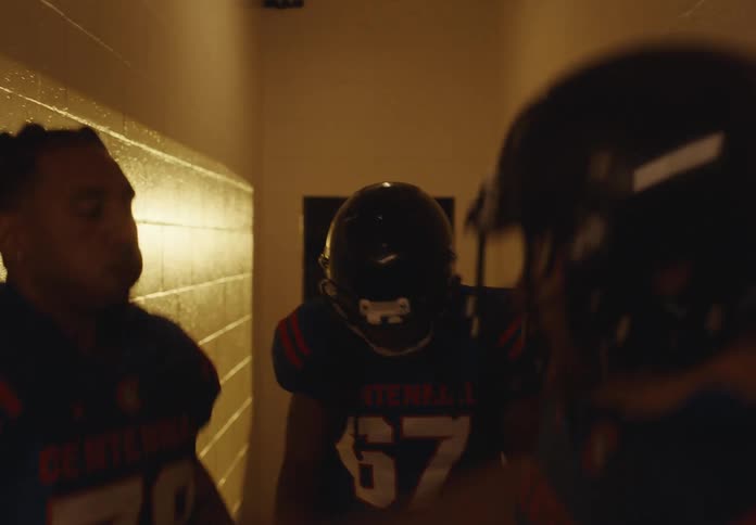 Football players walk through a lit hallway before the game