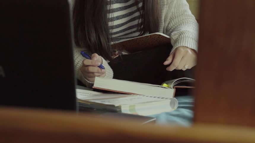 A woman marks in a textbook with a highlighter