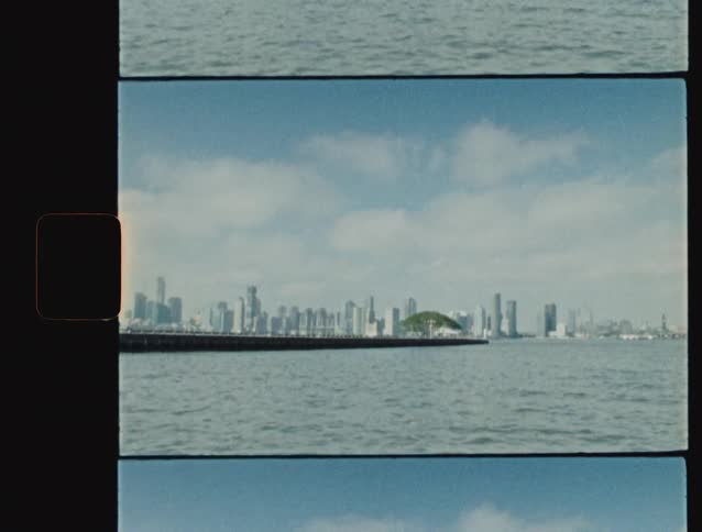 A view of the panama city skyline and the amador causeway from the ocean filmed on 16mm film stock with a bright blue sky and choppy water
