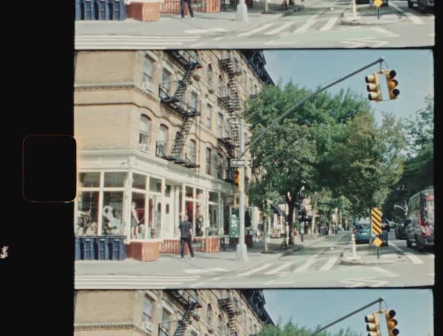 Cars drive along a street that is lined with apartment buildings