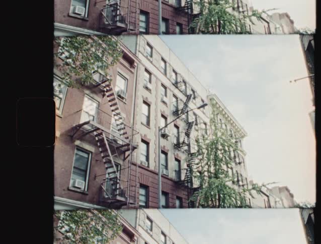 Fire escapes run down the side of an apartment building on a cloudy day
