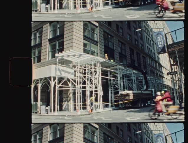 The video styled with a vintage film look shows a street corner in a city a soho banner is visible on the rightconstruction workers are present around a building corner where scaffolding is set up while a cyclist on a cargo bike rides past in t