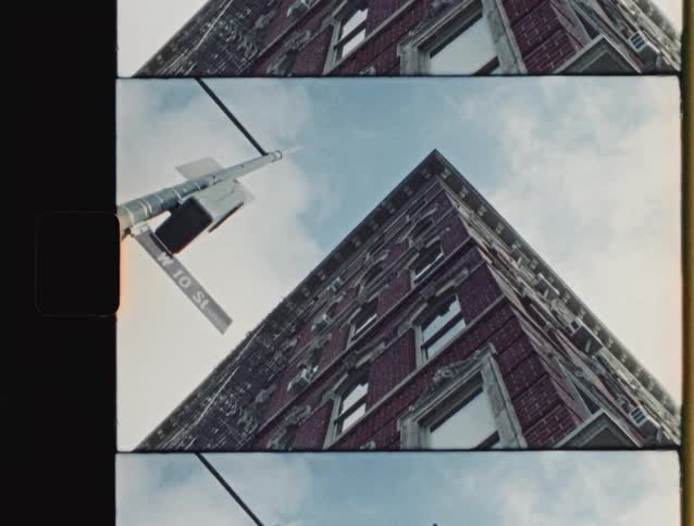 Street sign and brick building facade are seen from a low angle against the sky