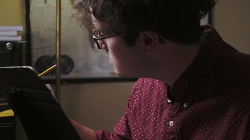 A man writes on a music sheet with a pencil