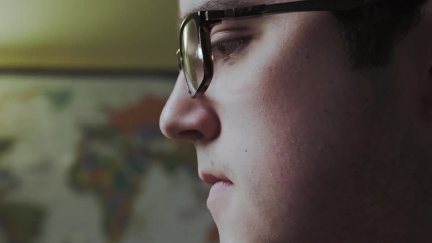 A man in glasses touches a pencil eraser to his chin