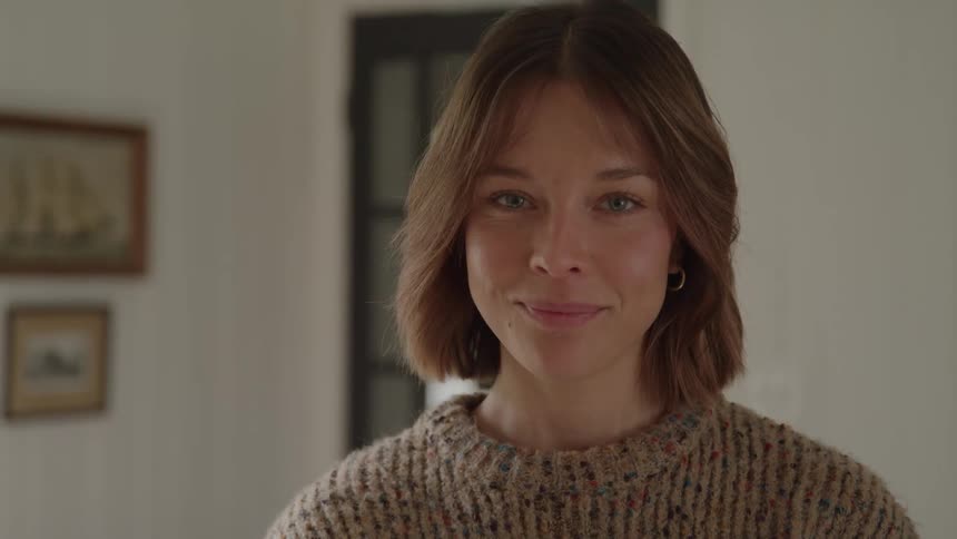 Woman in a beige sweater inside a domestic setting