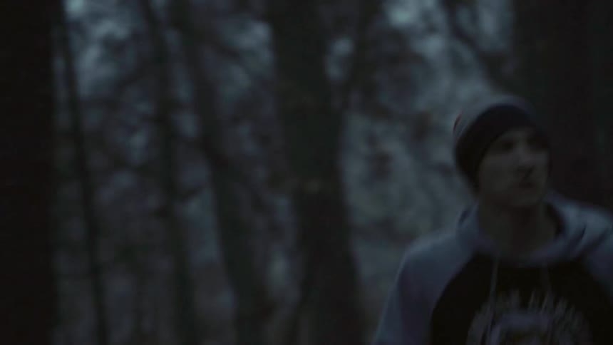 A man is jogging in a wooded area on a cold day