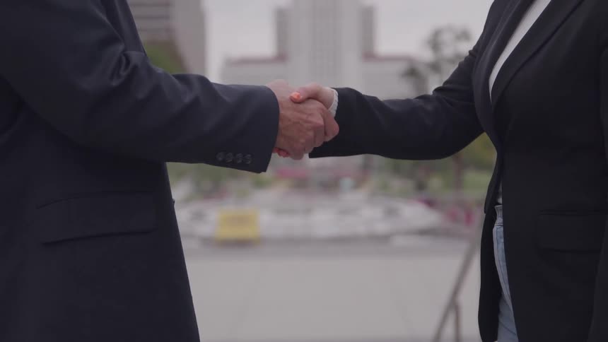 Two people shaking hands outdoors