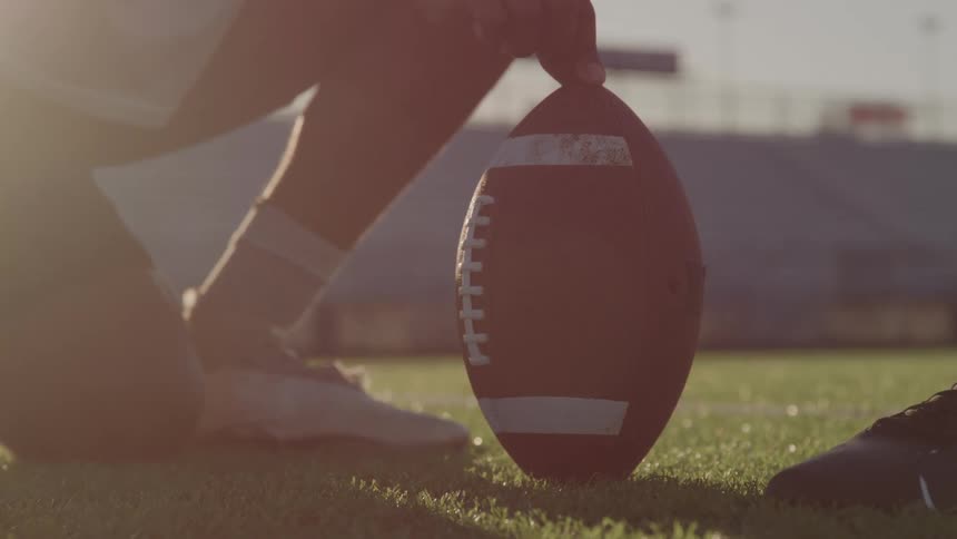 Person kicks a ball on a field lit by low sunlight
