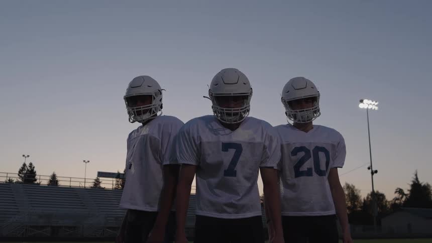 Three players stand side by side on the field