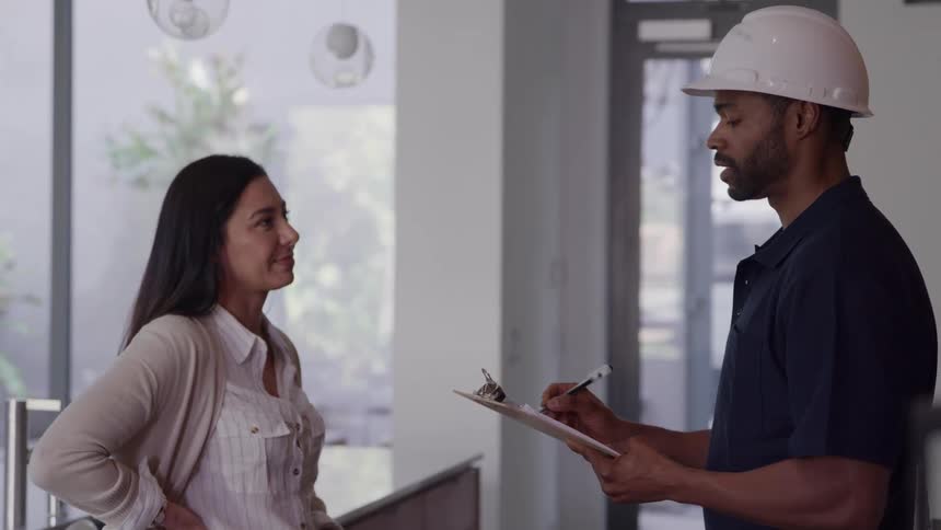 Woman stands talking to a utility worker in her house