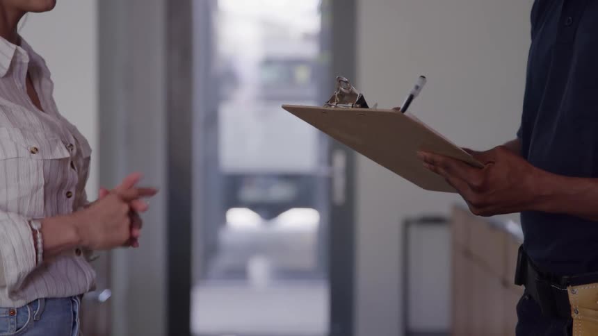 Woman gesturing speaks with a professional writing on a clipboard